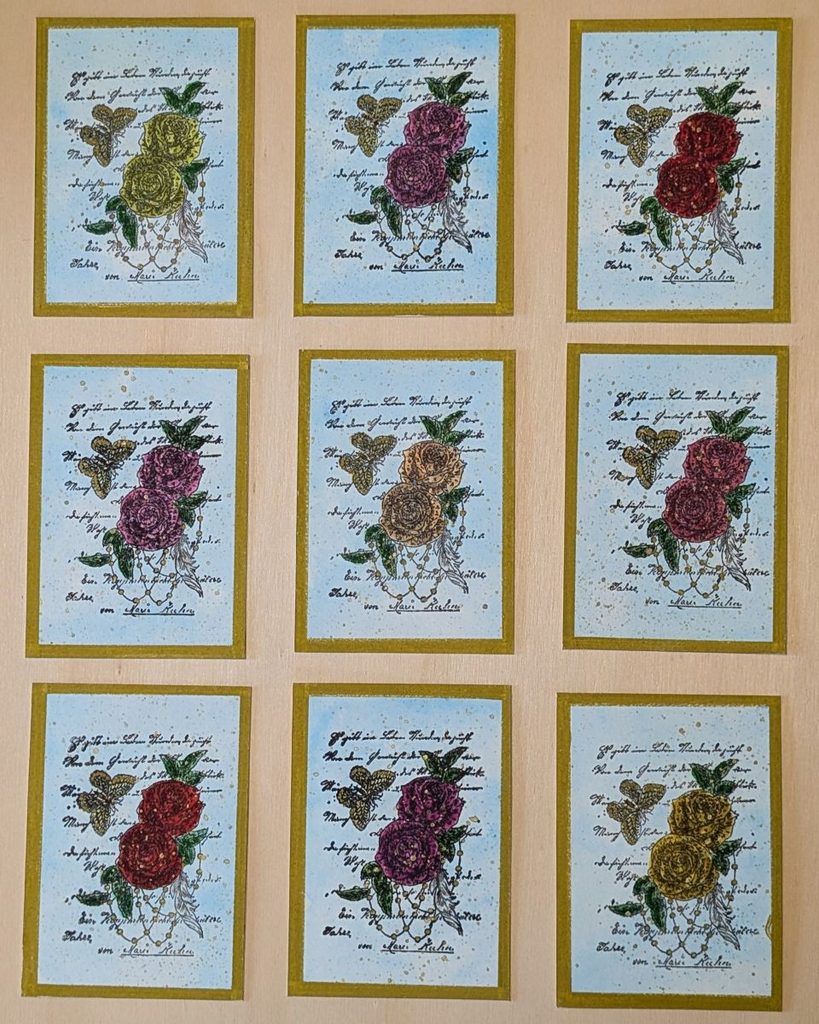 Neun ATCs der Serie Rosen mit Stempelmotiv aus Rosen und Schmetterling auf zartblauem Hintergrund, bunt koloriert und mit Gold akzentuiert